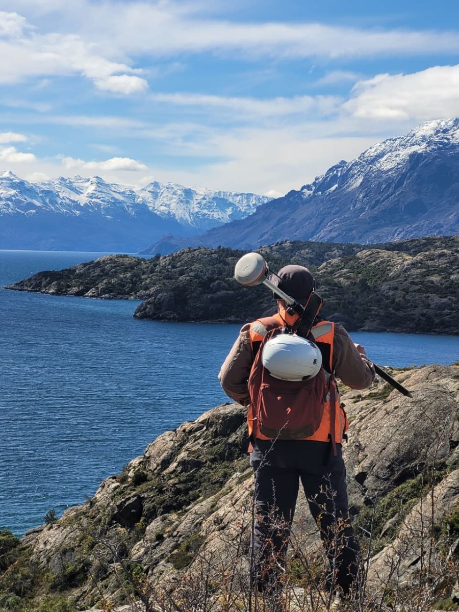 Profesional con equipo GNSS frente al lago y la cordillera